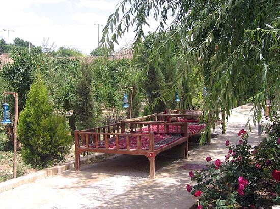 Two carpet covered takhts in a garden setting