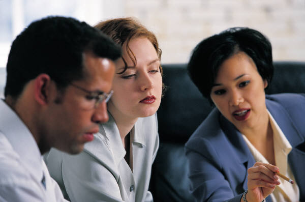 Two women and a man of different ethnic backgrounds in discussion, collabotaing and working as a team